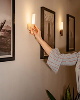 Person lifting the glowing light away from its wall mount indoors