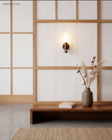 Lit tube sconce on a white wall beside a shoji screen and bench
