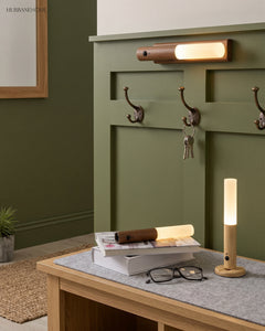 Cordless wood lamp resting on a table by a green panelled entry wall
