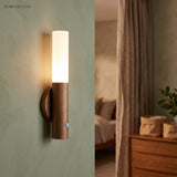 Warm lit sconce on a green bedroom wall beside an open doorway