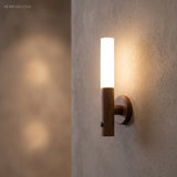 Walnut wall sconce casting a soft pool of light on textured plaster