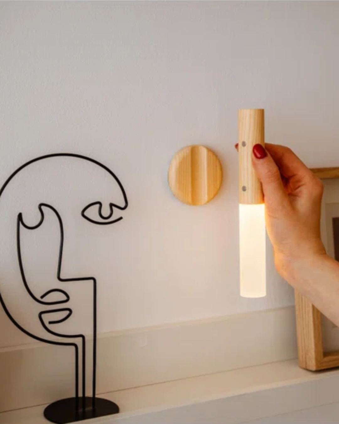 Hand placing the lit tube back onto its round wall mount