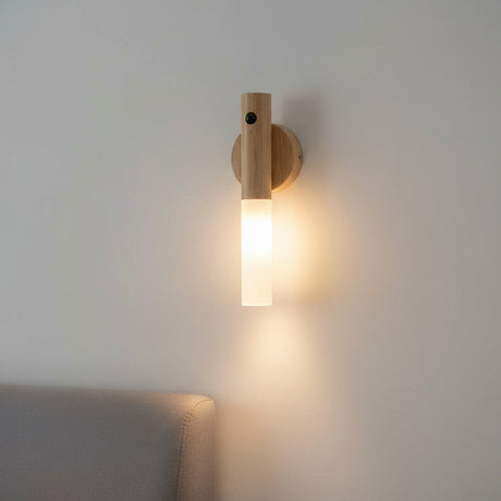 Light oak sconce lit on a pale wall above a grey sofa