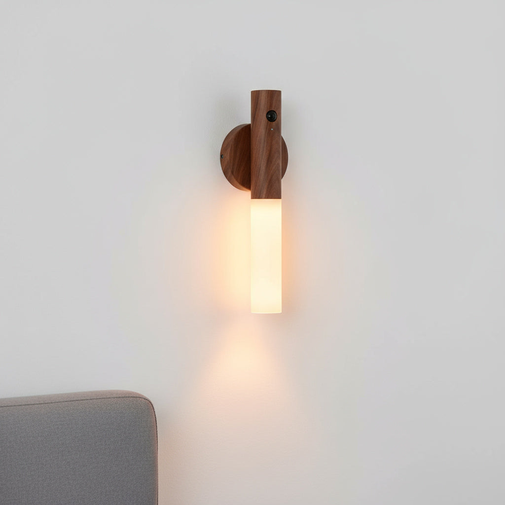 Dark walnut sconce lit on a pale wall above a grey sofa