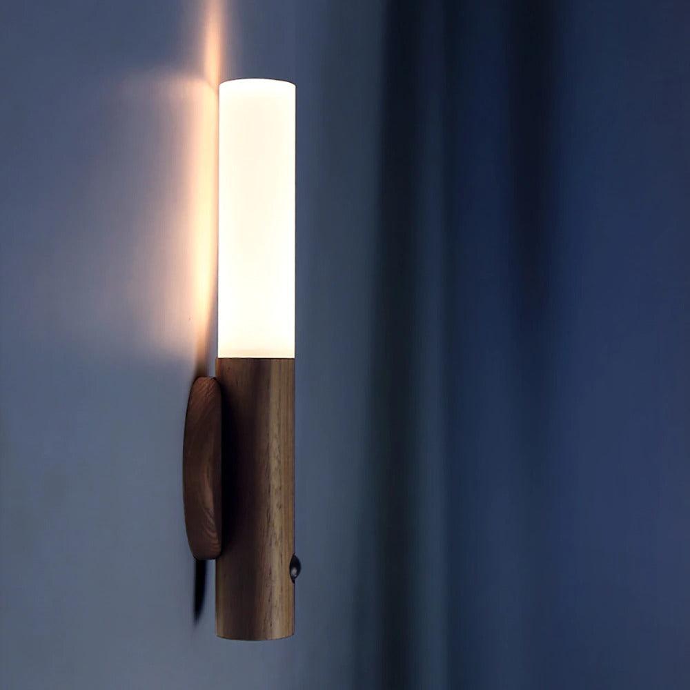 Dark walnut sconce lit against a deep blue painted wall