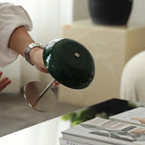 A hand lifting the cordless green dome lamp by its slim stem
