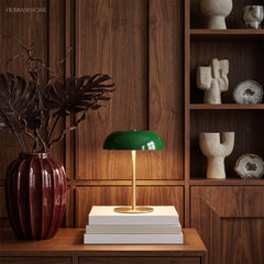 Green dome lamp on stacked books in front of walnut shelving