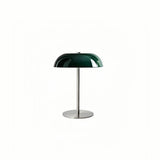 Green dome table lamp with a slim stem and round base on white