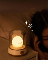 Night light on a nightstand with someone lying in bed just behind it