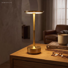 Brass dish table lamp lit on a wooden desk beside a chair