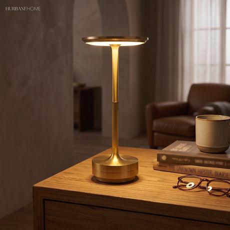 Brass dish table lamp lit on a wooden desk beside a chair