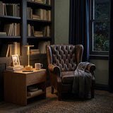 Dish lamp lighting a dark panelled study with armchair behind