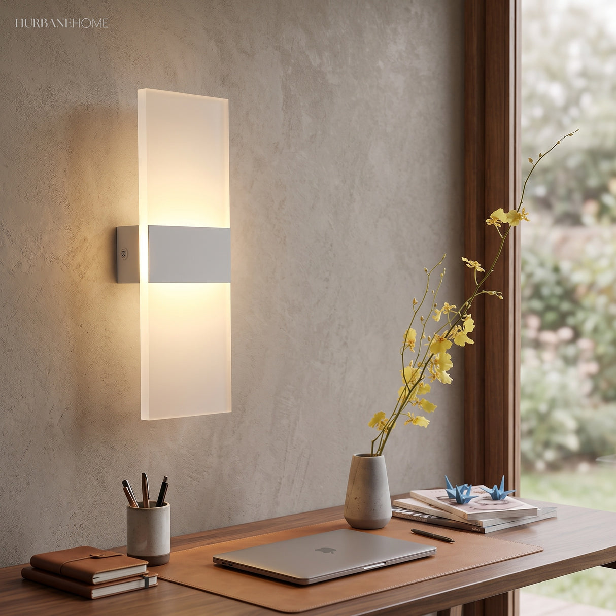 Acrylic panel wall light lit above a desk with books and a vase