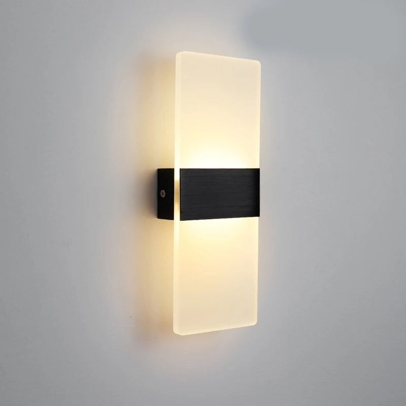 Black acrylic panel wall light lit on a plain grey wall