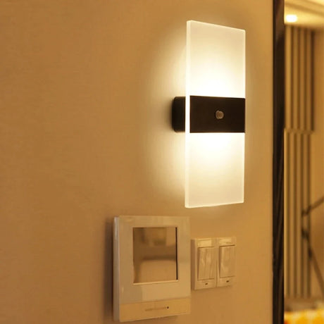 Acrylic panel wall light lit on a warm ochre wall beside a switch