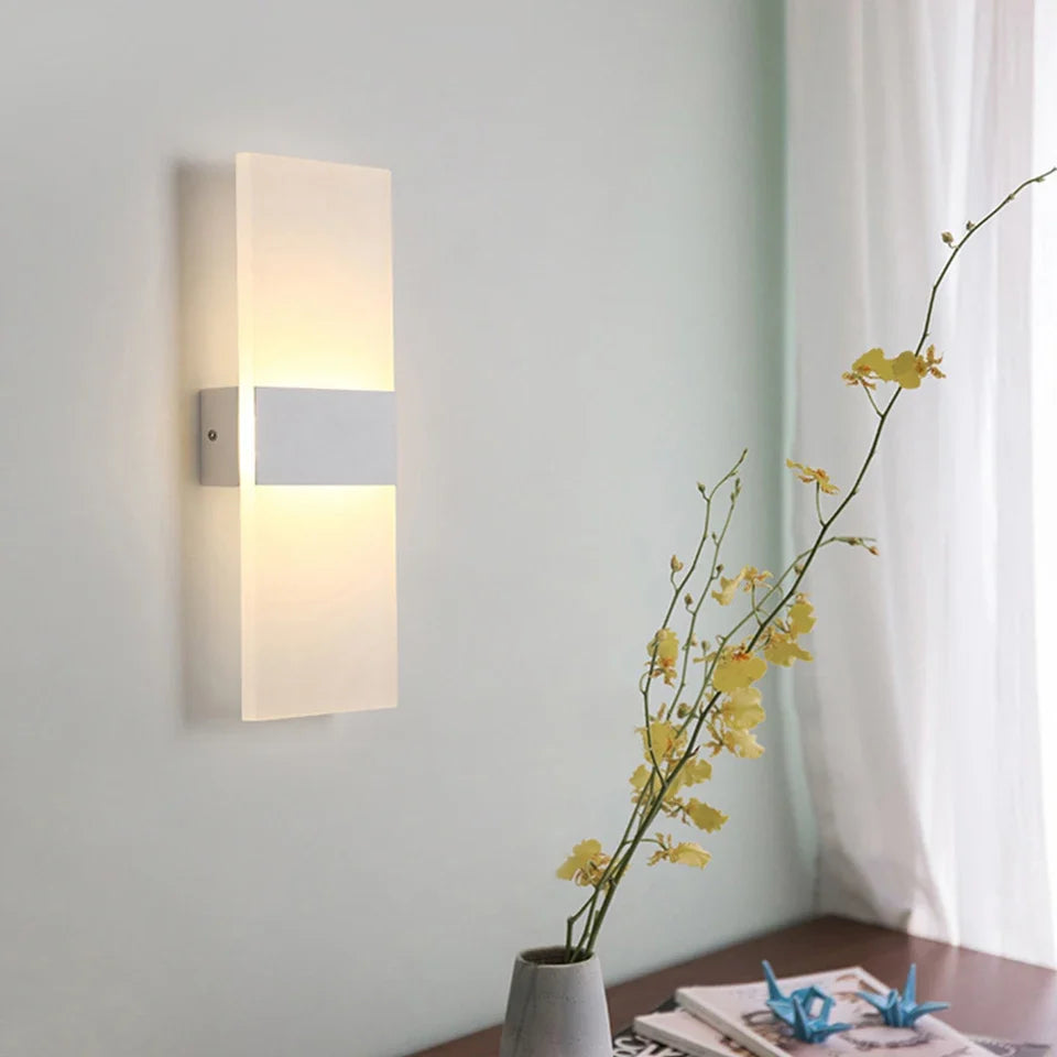 White acrylic panel wall light lit on a pale wall