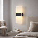 Black and acrylic rechargeable wall light lit beside a bed