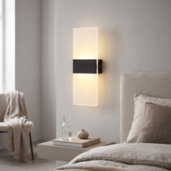 Black and acrylic rechargeable wall light lit beside a bed