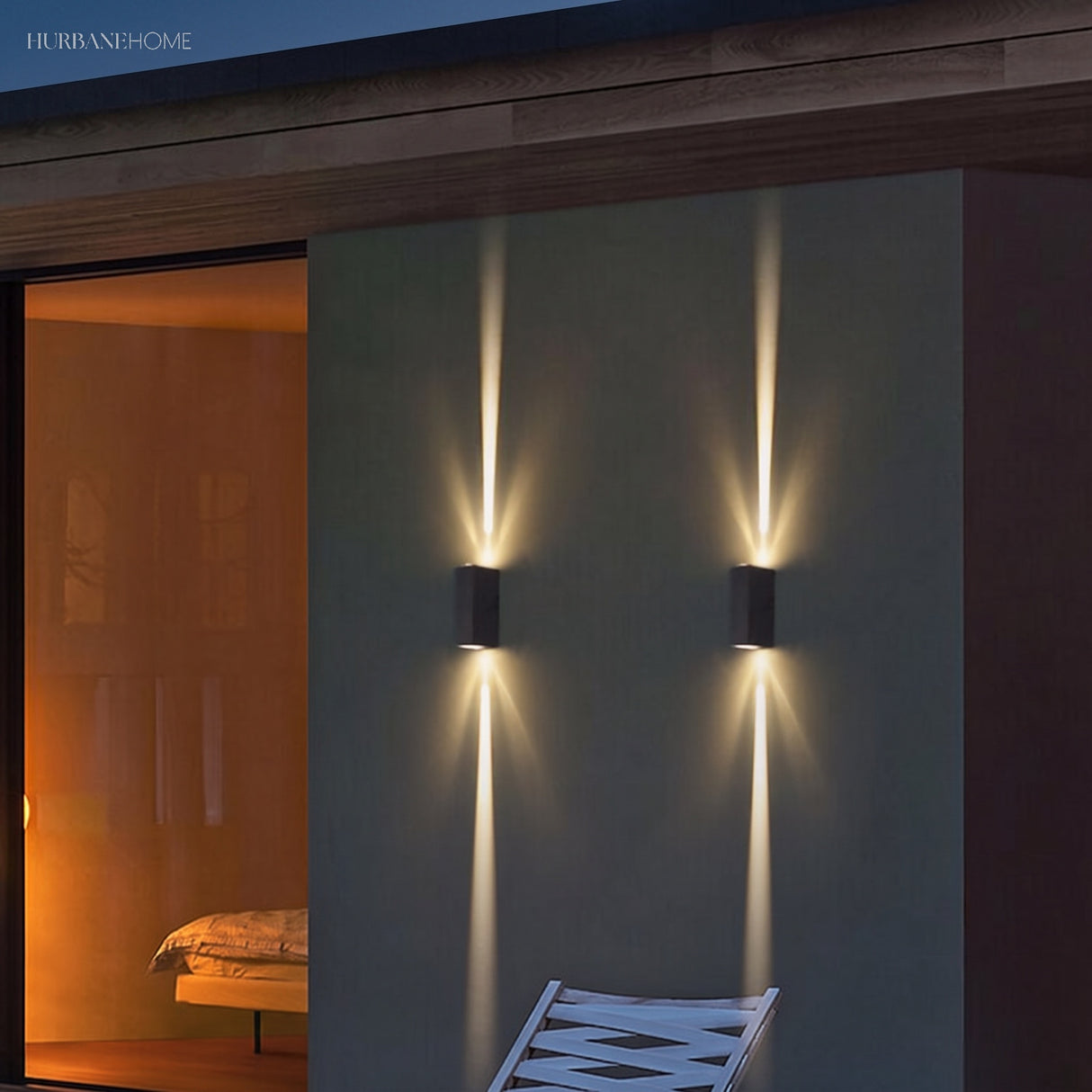 Two black outdoor wall sconces casting twin beams on a grey exterior wall at dusk
