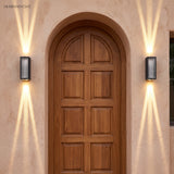 Pair of up and down wall lights flanking an arched wooden door on tan plaster