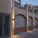 Two black wall lights lighting a beige facade above garage arches at dusk