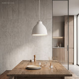 White dome pendant lighting a timber dining table beside concrete wall