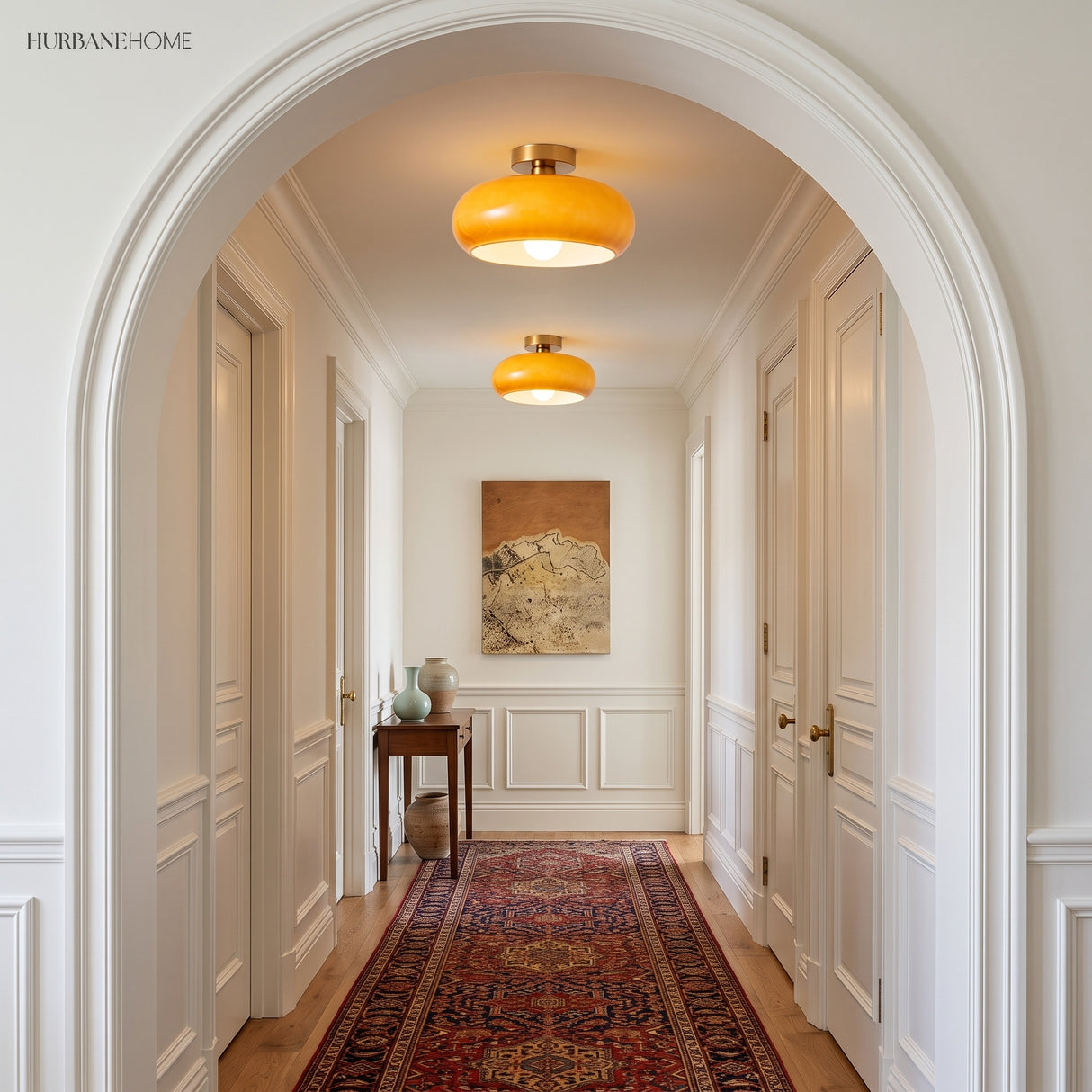 Two amber glass flush mount lights lighting a white arched entry hallway