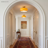 Two amber glass flush mount lights lighting a white arched entry hallway