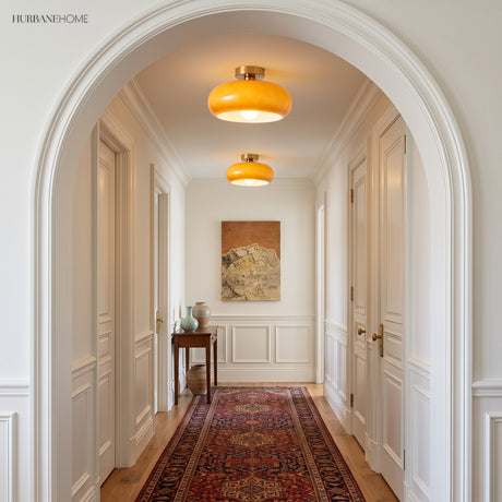 Two amber glass flush mount lights lighting a white arched entry hallway
