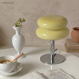 Yellow glass table lamp on a round table with a vase and coffee cup