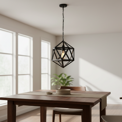 A black metal geometric pendant light hangs over a wooden dining table in a bright, modern dining room with large windows and soft natural light.