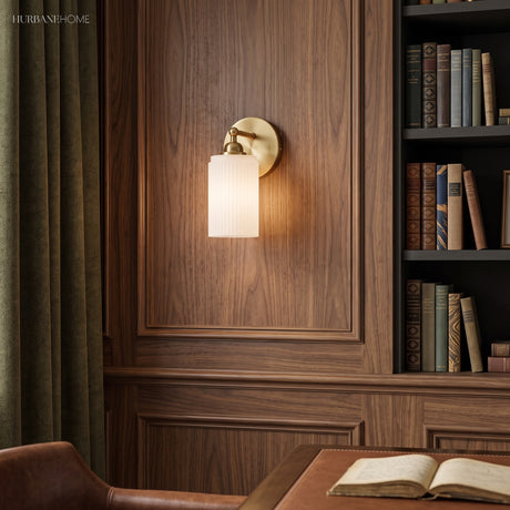 Ribbed glass sconce on walnut panelling above an open book and desk