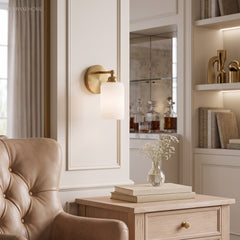 Ribbed glass sconce in a cream panelled room beside a tufted armchair