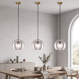 Row of three ribbed glass globes with brass fittings over a long dining table
