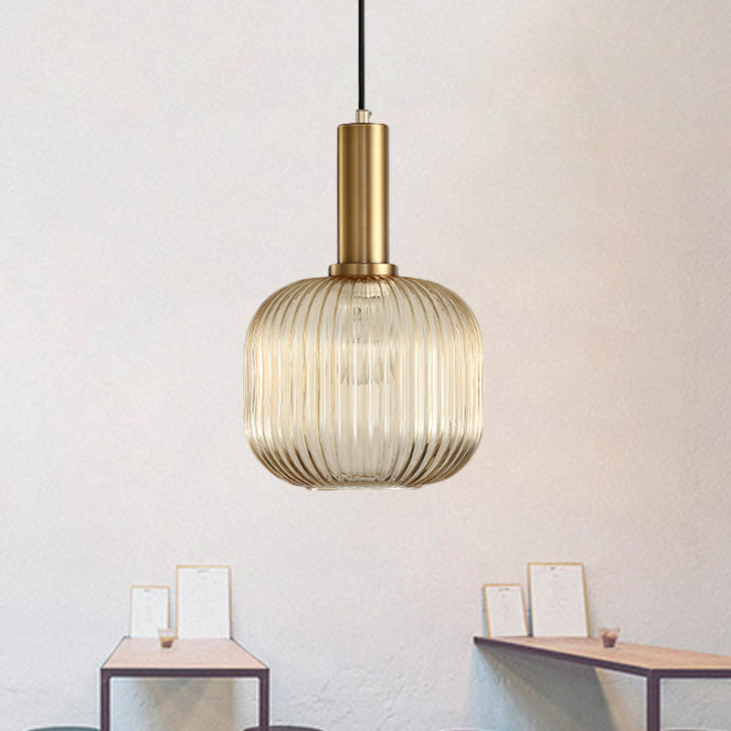 Amber ribbed capsule pendant lit on a pale wall by small frames