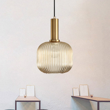Amber ribbed capsule pendant lit on a pale wall by small frames