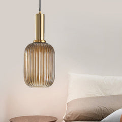Amber ribbed capsule pendant lit beside a bed in a pink room