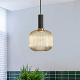 Amber ribbed pendant lit in a white room by green wall tiles