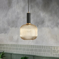 Amber ribbed pendant lit against a wall of green subway tiles