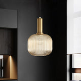Amber ribbed pendant lit above a bench in a dark kitchen