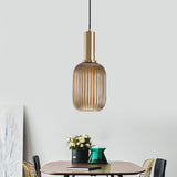 Amber ribbed pendant lit above a dining table and potted plant