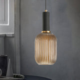 Amber ribbed pendant lit warm against a plain grey wall