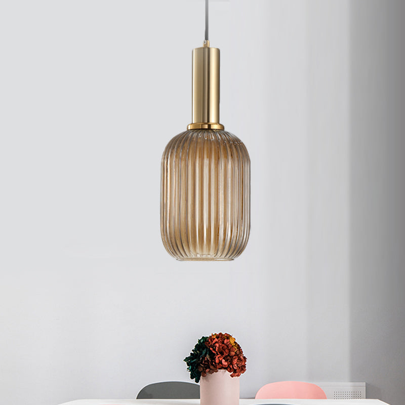 Amber ribbed pendant lit in a pale room beside a pink vase