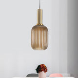 Amber ribbed pendant lit in a pale room beside a pink vase