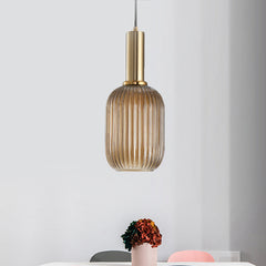 Amber ribbed pendant lit in a pale room beside a pink vase