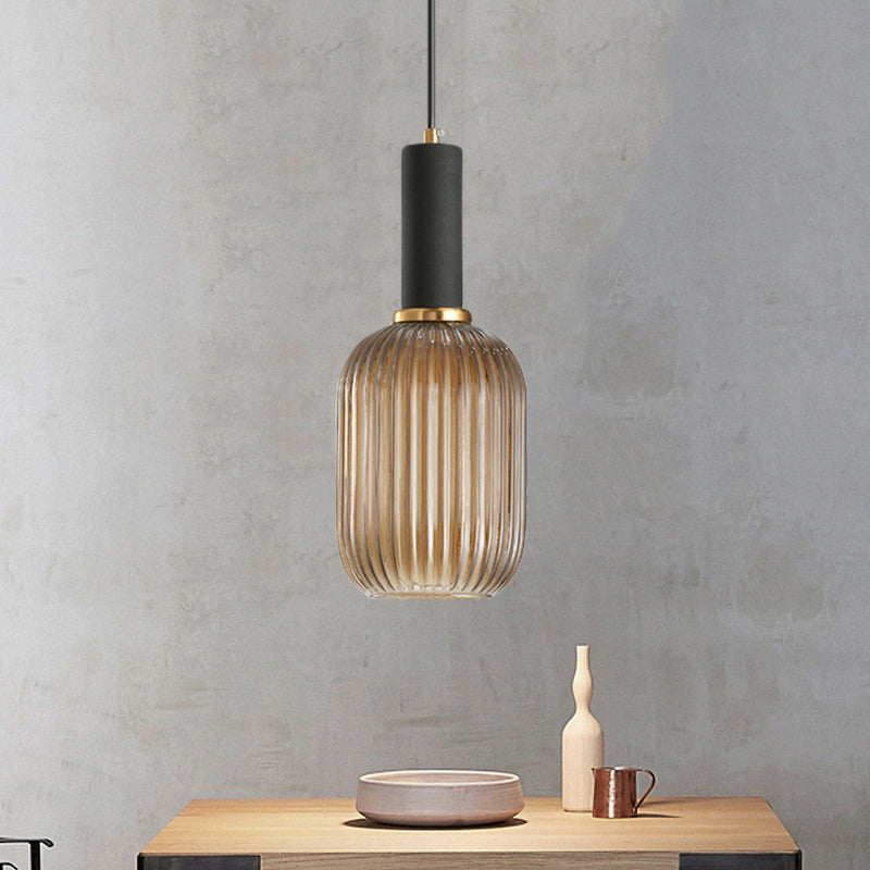 Amber ribbed pendant lit on a grey wall above a small table