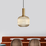 Amber ribbed pendant lit above a tan sofa and dining chairs