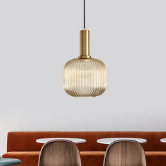Amber ribbed pendant lit above a tan sofa and dining chairs
