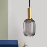 Green ribbed capsule pendant lit on a green wall by a blue chair