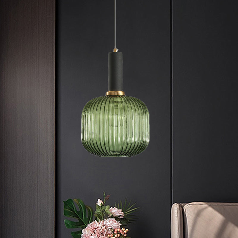 Green ribbed pendant lit on a dark wall above cut flowers